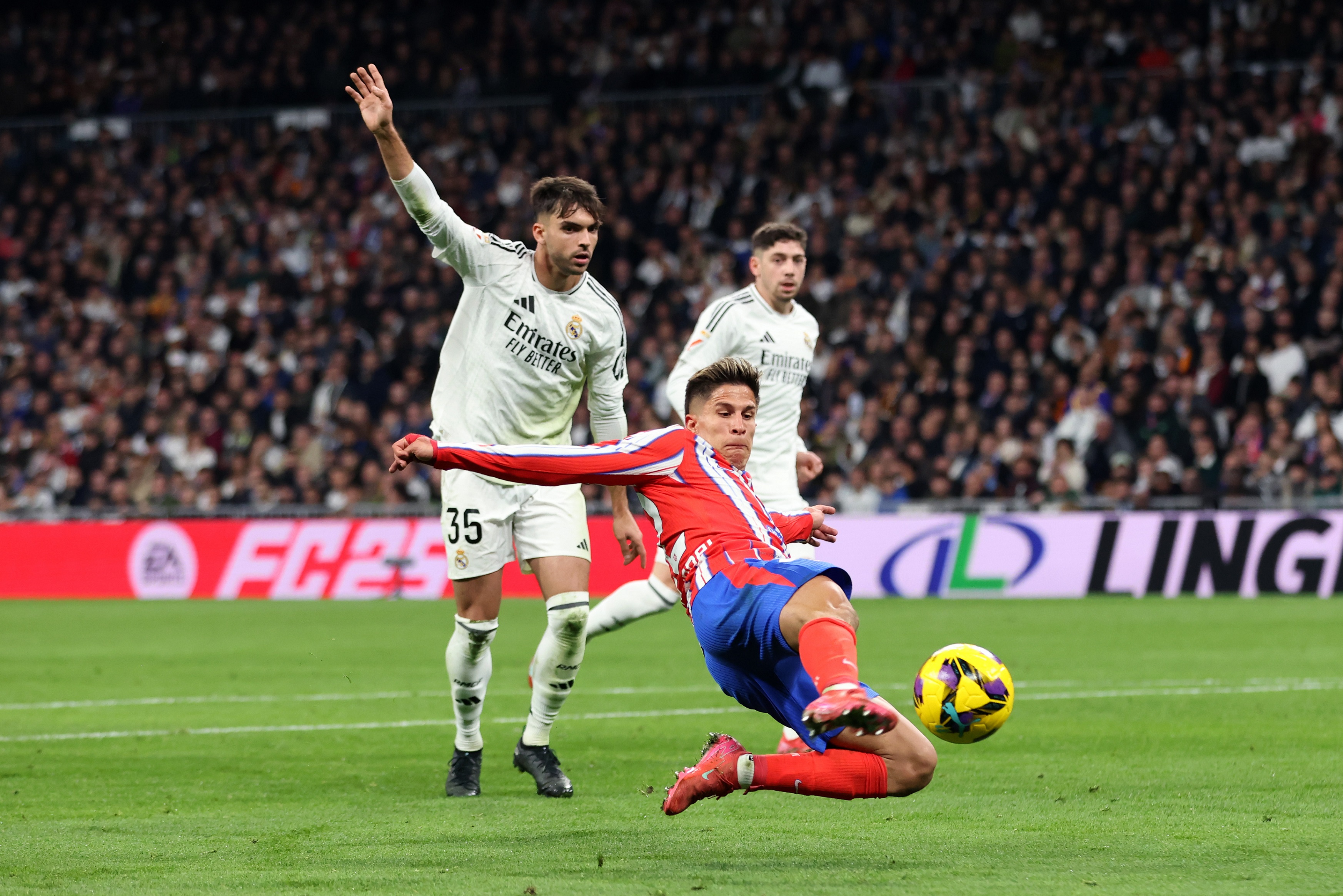 MADRID, SPAIN - FEBRUARY 08: Giuliano Simeone of Atletico de Madrid is challenged by Raul Asencio of Real Madrid during the LaLiga match between Real Madrid CF and Atletico de Madrid at Estadio Santiago Bernabeu on February 08, 2025 in Madrid, Spain.