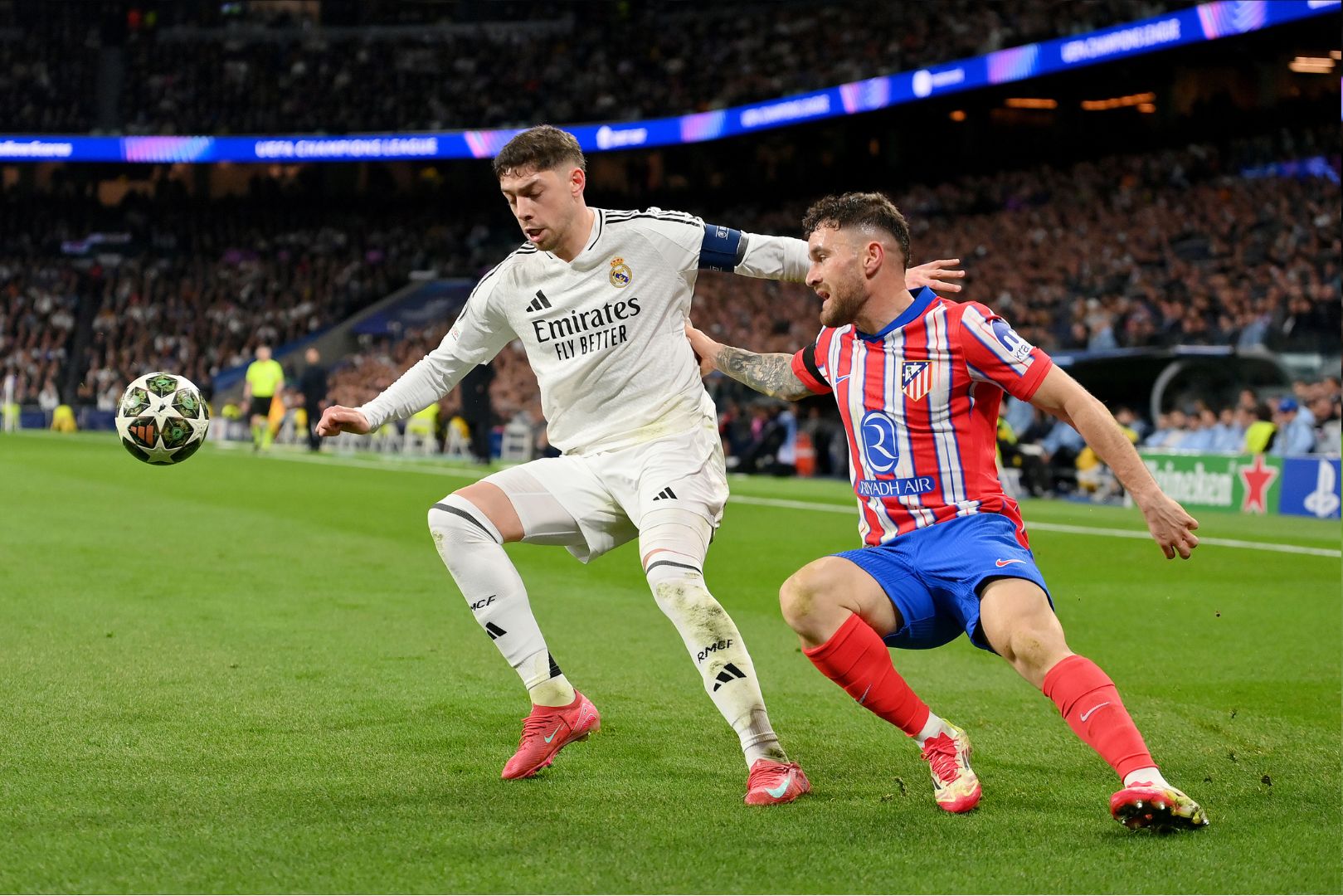 MADRID, SPAIN - MARCH 04: Federico Valverde of Real Madrid is challenged by Javi Galan of Atletico de Madrid during the UEFA Champions League 2024/25 Round of 16 first leg match between Real Madrid C.F. and Atletico de Madrid at Santiago Bernabeu Stadium on March 04, 2025 in Madrid, Spain.