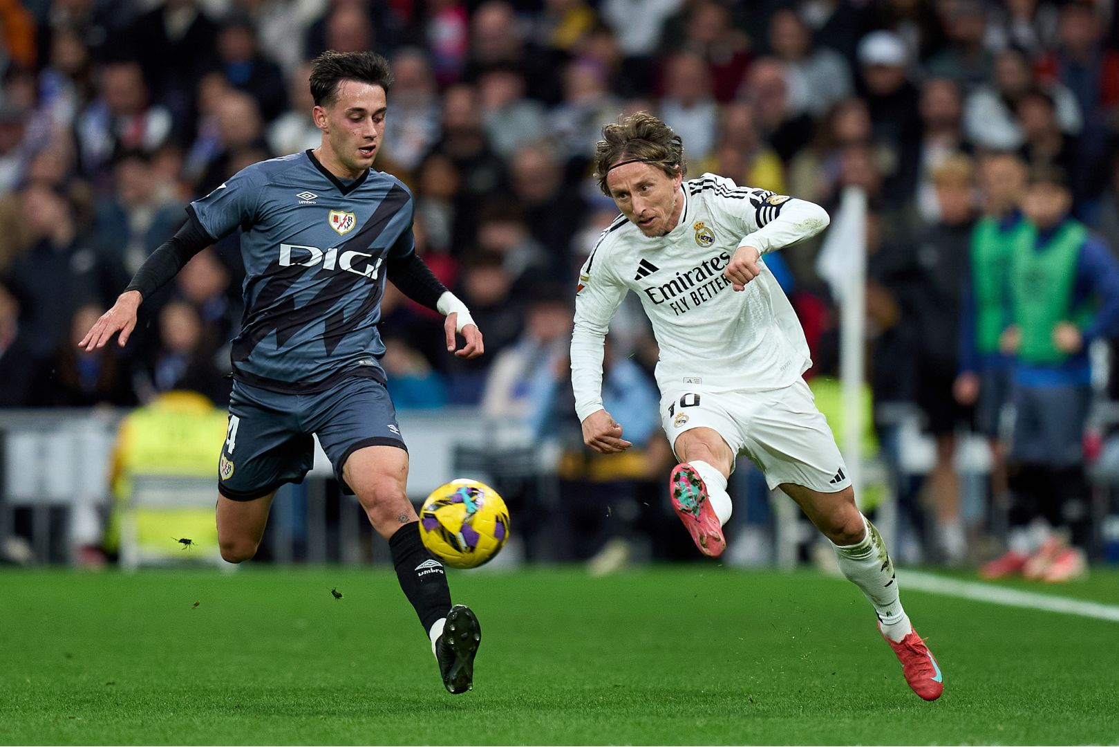 MADRID, SPAIN - MARCH 09: Luka Modric of Real Madrid passes the ball whilst under pressure from Pedro Díaz r during the LaLiga match between Real Madrid CF and Rayo Vallecano at Estadio Santiago Bernabeu on March 09, 2025 in Madrid, Spain.