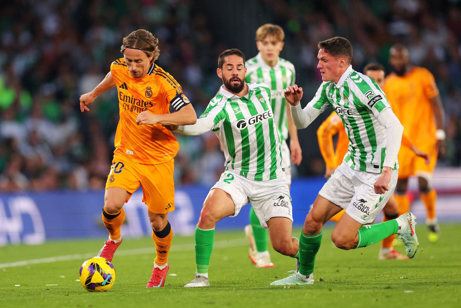 SEVILLE, SPAIN - MARCH 01: Luka Modric of Real Madrid runs with the ball whilst under pressure from Isco and Sergi Altimira of Real Betis during the LaLiga match between Real Betis Balompie and Real Madrid CF at Estadio Benito Villamarin on March 01, 2025 in Seville, Spain.
