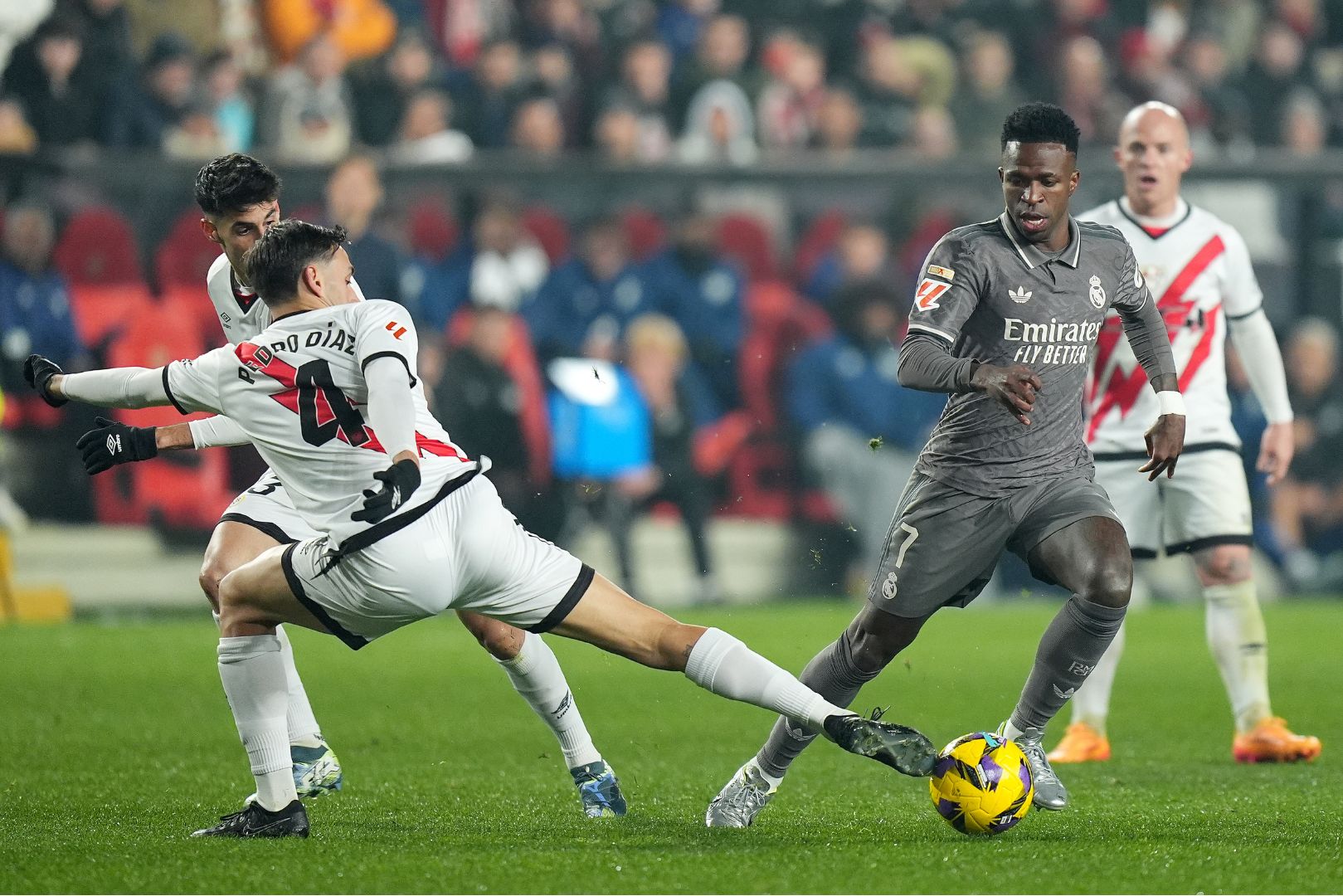 MADRID, SPAIN - DECEMBER 14: Vinicius Junior of Real Madrid is challenged by Pedro Diaz of Rayo Vallecano during the LaLiga EA Sports match between Rayo Vallecano and Real Madrid at Estadio de Vallecas on December 14, 2024 in Madrid, Spain.