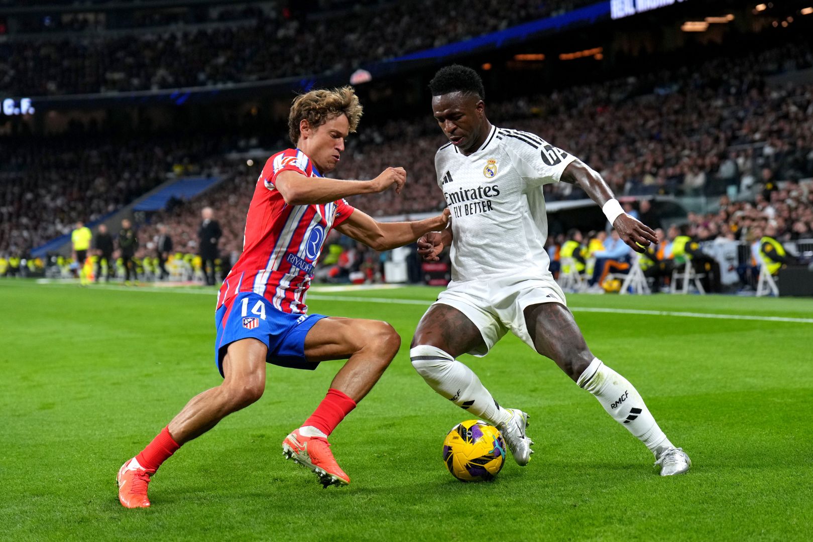 MADRID, SPAIN - FEBRUARY 08: Vinicius Junior of Real Madrid is challenged by Marcos Llorente of Atletico de Madrid during the LaLiga match between Real Madrid CF and Atletico de Madrid at Estadio Santiago Bernabeu on February 08, 2025 in Madrid, Spain.